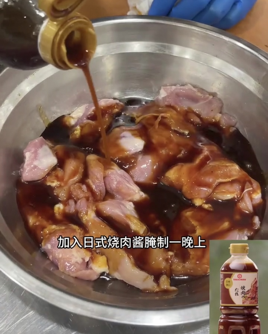 Muslos de pollo deshuesados sumergidos en salsa teriyaki en un bol de acero inoxidable.