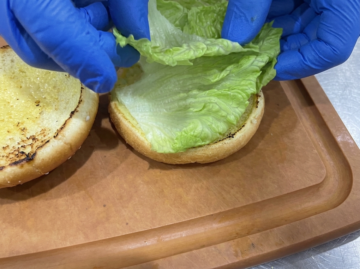 Hojas de lechuga verde sobre la base tostada del pan de hamburguesa.