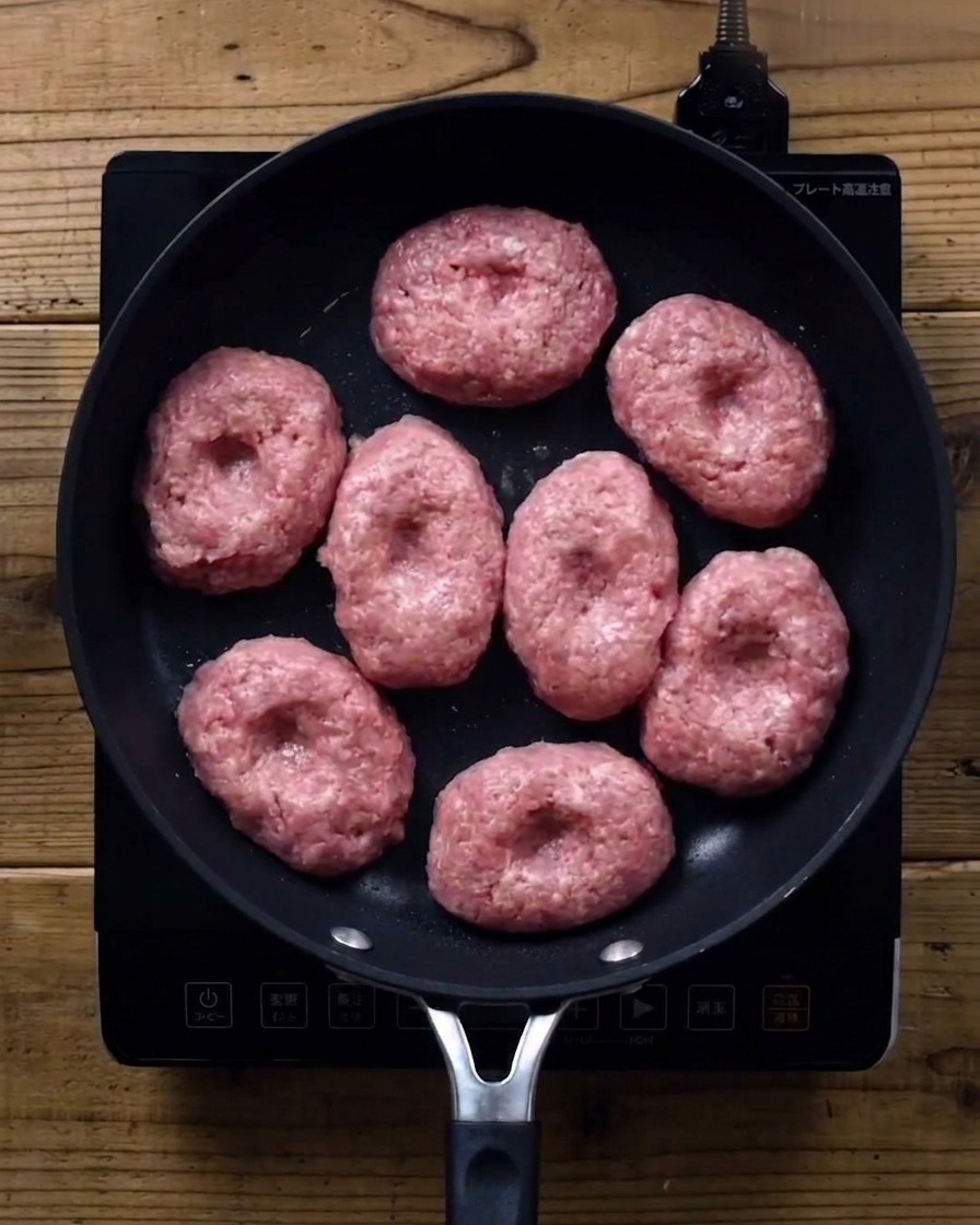 Hamburguesas en una sartén cubiertas con una tapa de cristal.