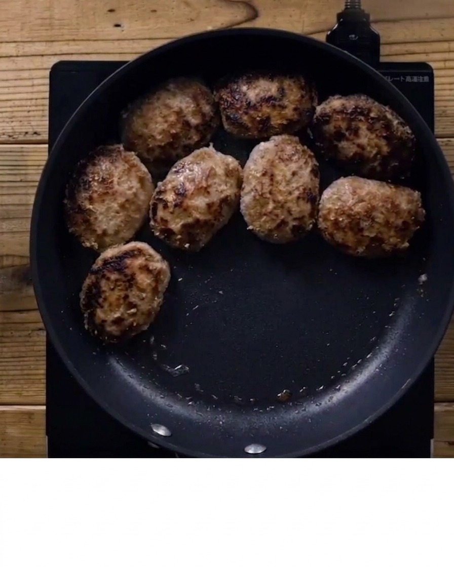 Salsa teriyaki siendo vertida sobre las hamburguesas doradas en la sartén.
