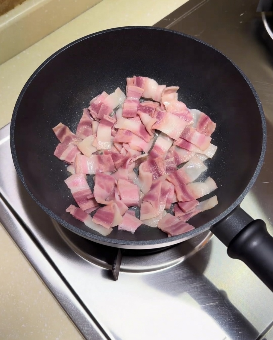 Trozos de bacon dorándose en una sartén con su propia grasa.