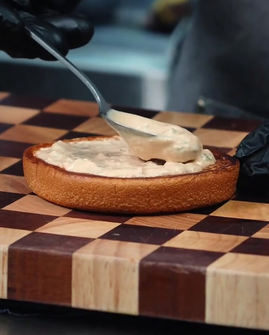 Lonchas de tomate fresco colocadas sobre la salsa en el pan de hamburguesa.