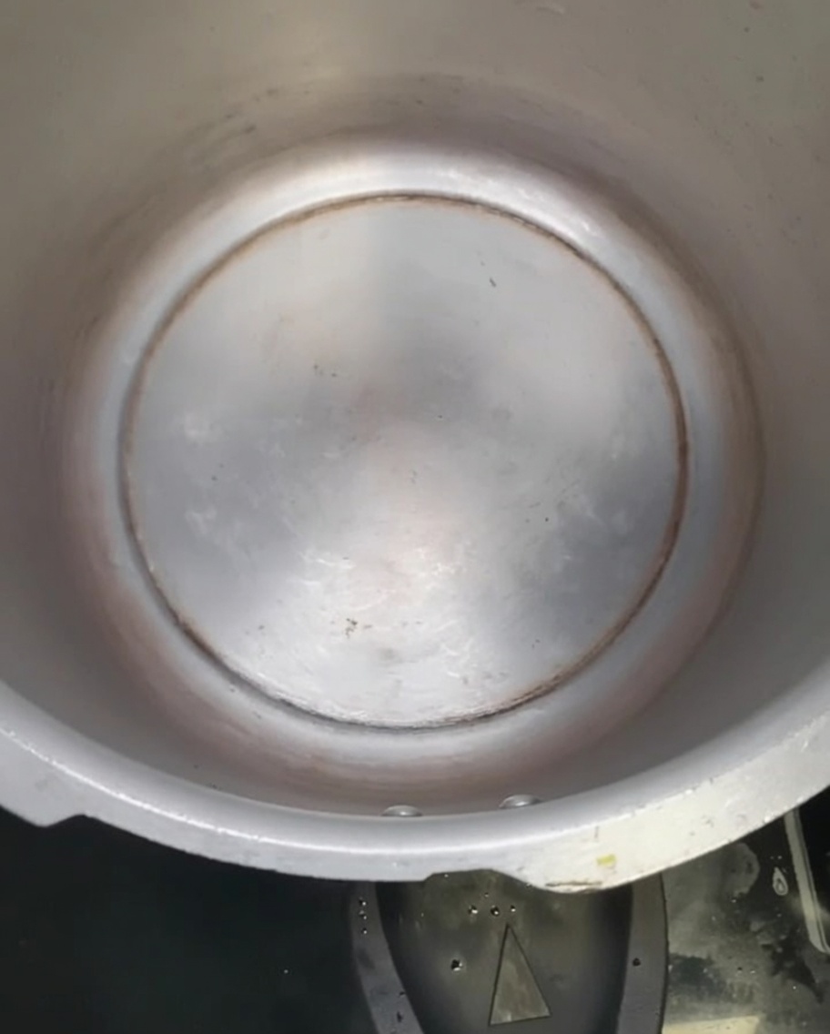 Aceite de maní brillando en el fondo de una olla a presión vacía.