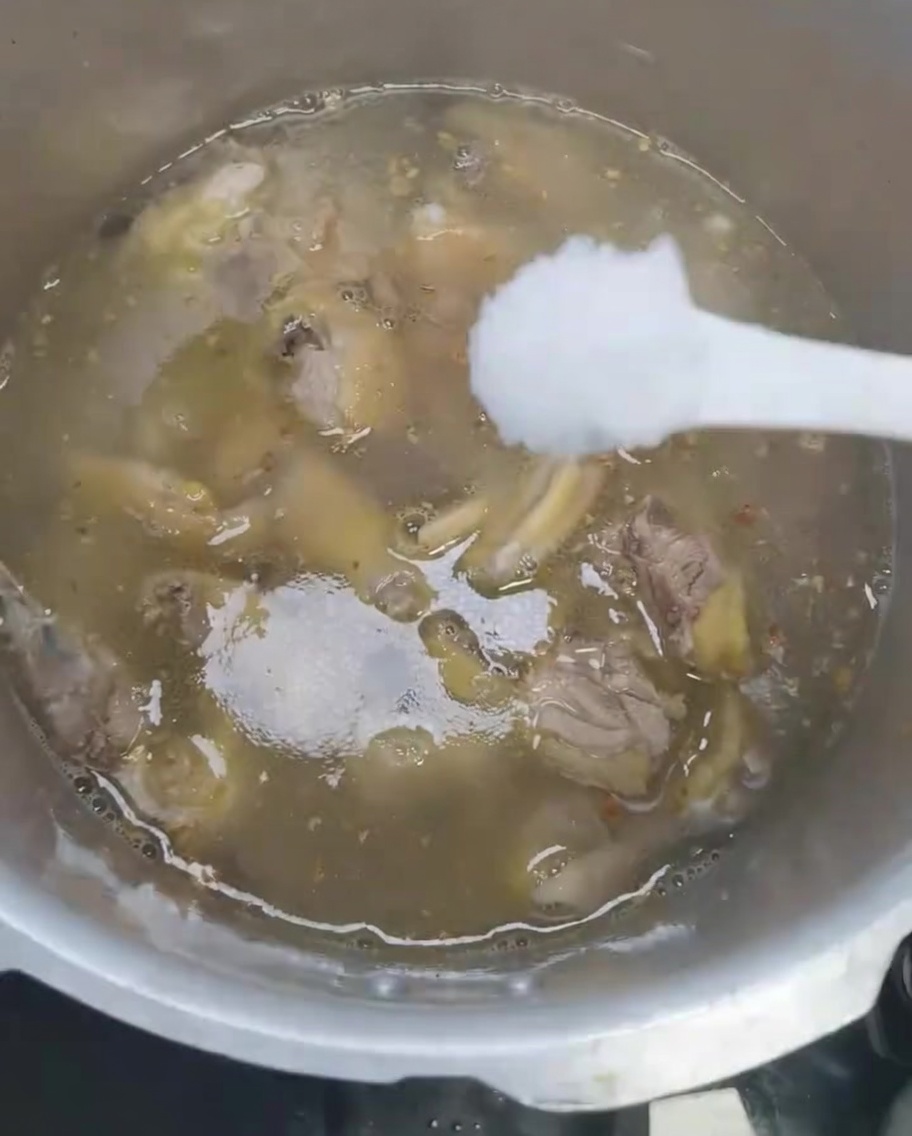 Sal siendo añadida a la sopa de pollo en la olla a presión.