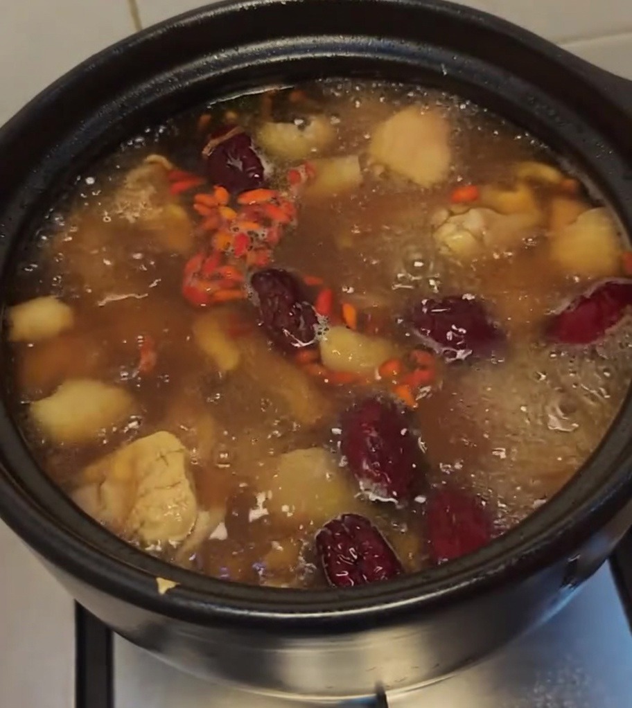 Sopa de pollo hirviendo, decorada con bayas de goji rojas y dátiles.
