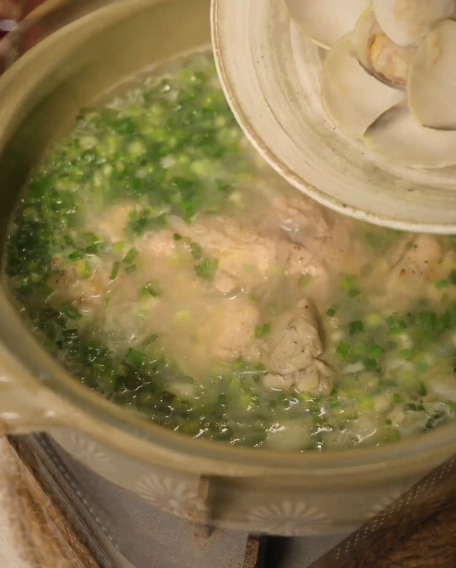 Tiras de cebolla y dientes de ajo dorándose en la grasa de pollo renderizada en una sartén.