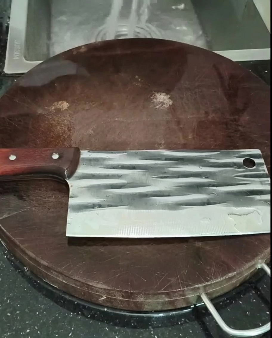 Piezas de pollo lavándose en un colador bajo el grifo de la cocina.