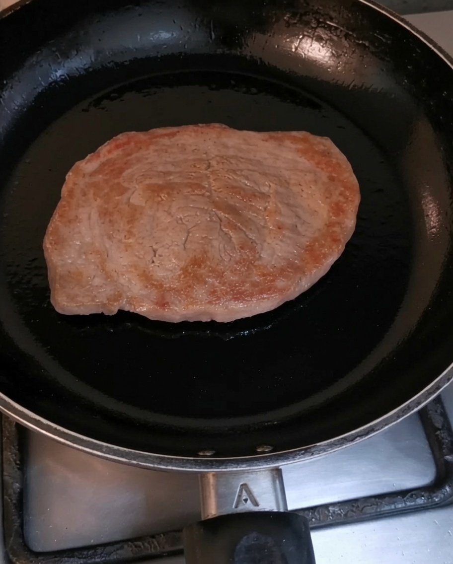 Un filete de ternera dorándose en una sartén caliente.