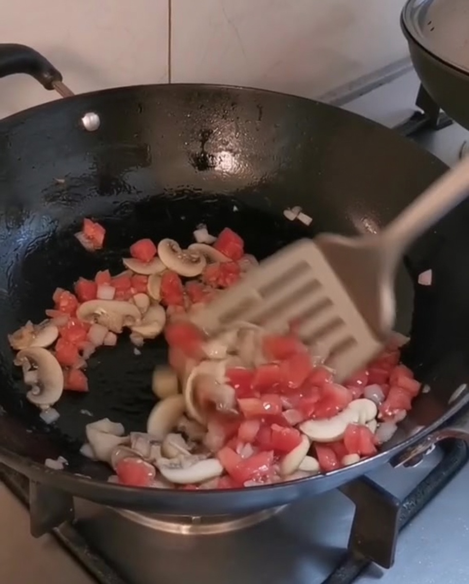 Vegetales picados y champiñones cocinándose en un wok caliente con aceite de oliva.