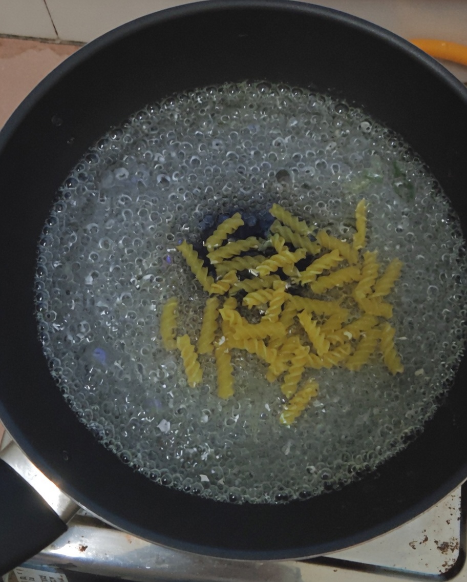 Pasta fusilli sumergida en una olla con agua hirviendo.