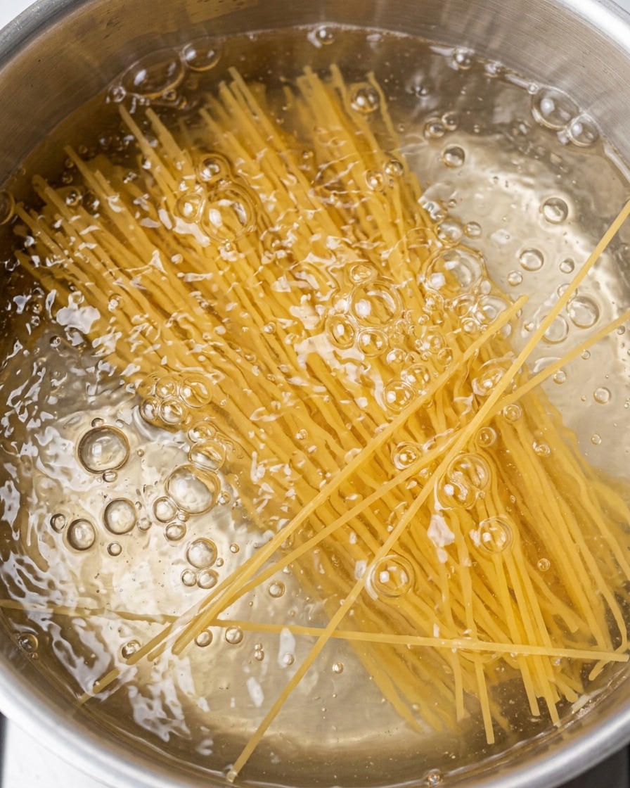 Fideos espagueti cocinándose en una olla con agua hirviendo.