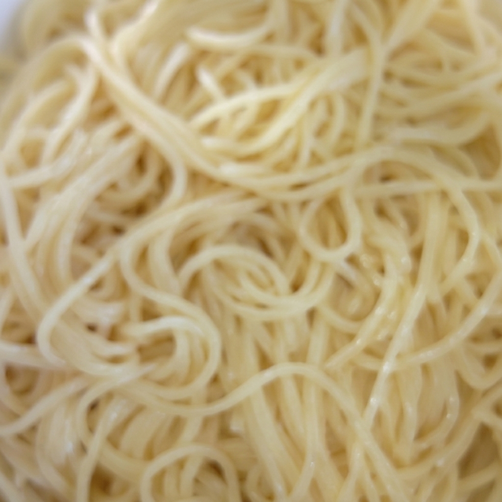 Un bol con espaguetis cocidos mezclándose con aceite.