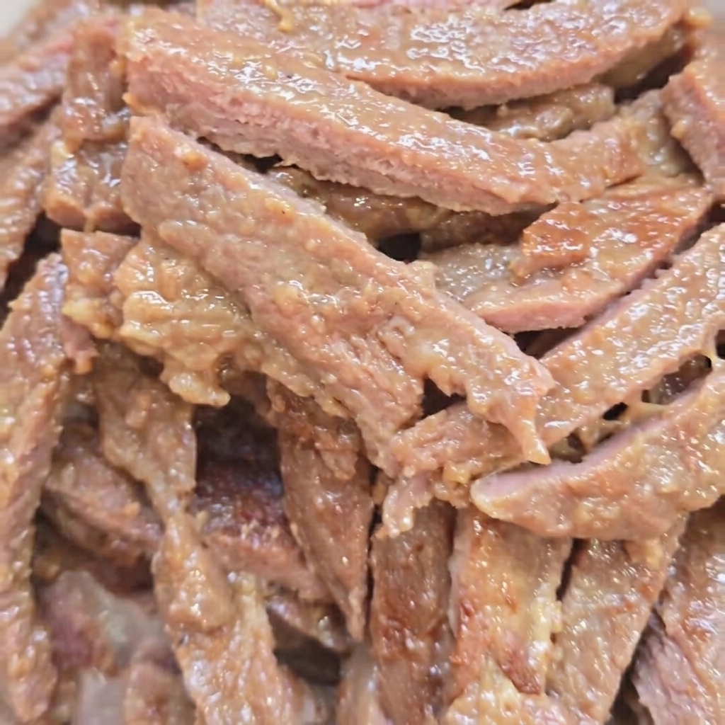 Tiras de carne dorándose en una sartén caliente.