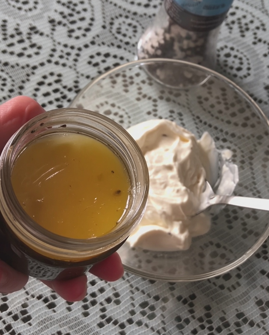 Una cucharada de salsa de trufa negra añadiéndose a un bol con crema agria blanca.