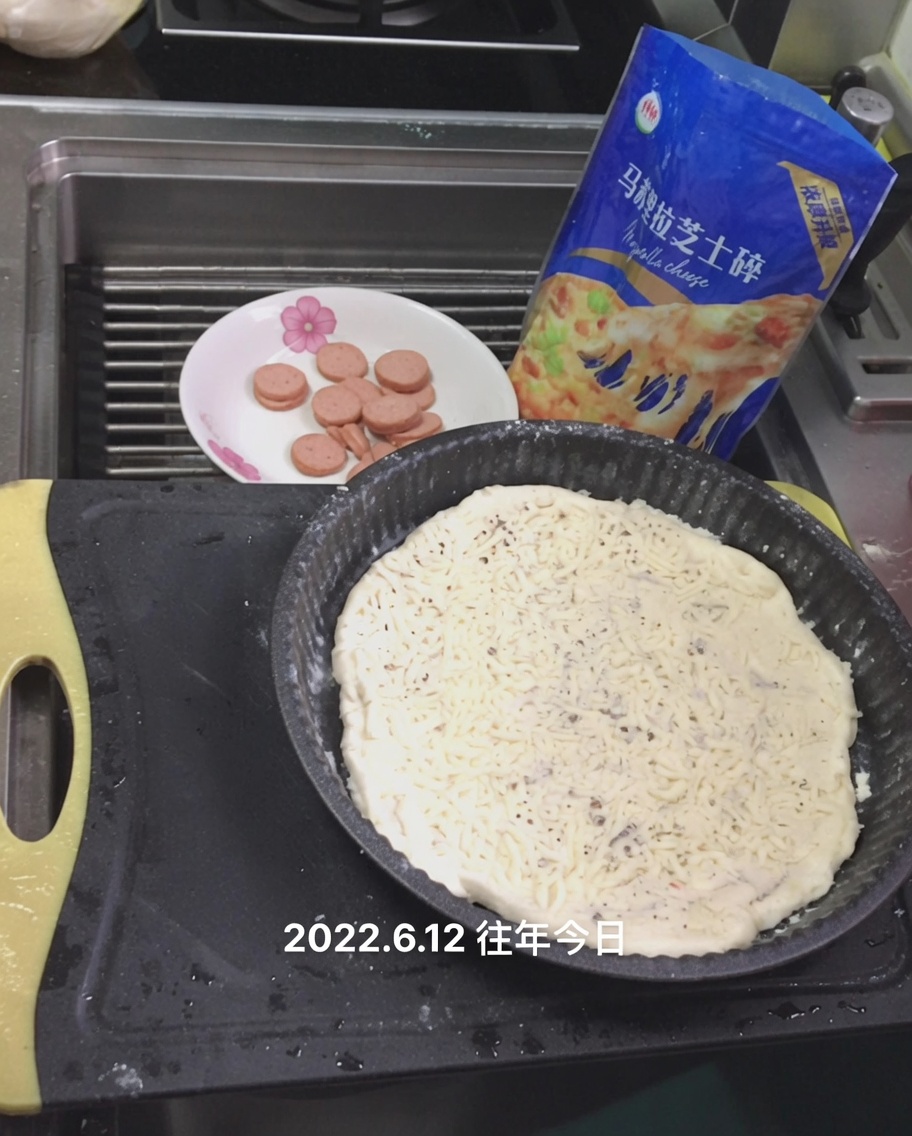 Queso mozzarella rallado siendo espolvoreado sobre la salsa blanca en la masa de pizza.