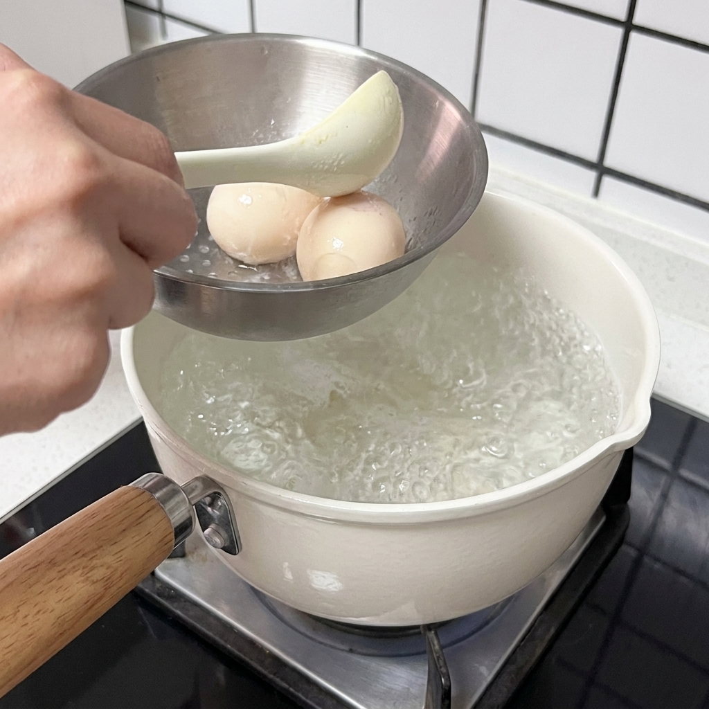 Huevos sumergidos en agua hirviendo en una olla blanca.
