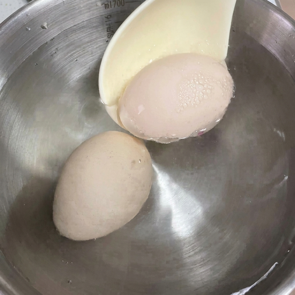 Huevos pasados por agua enfriándose en un bol con agua.