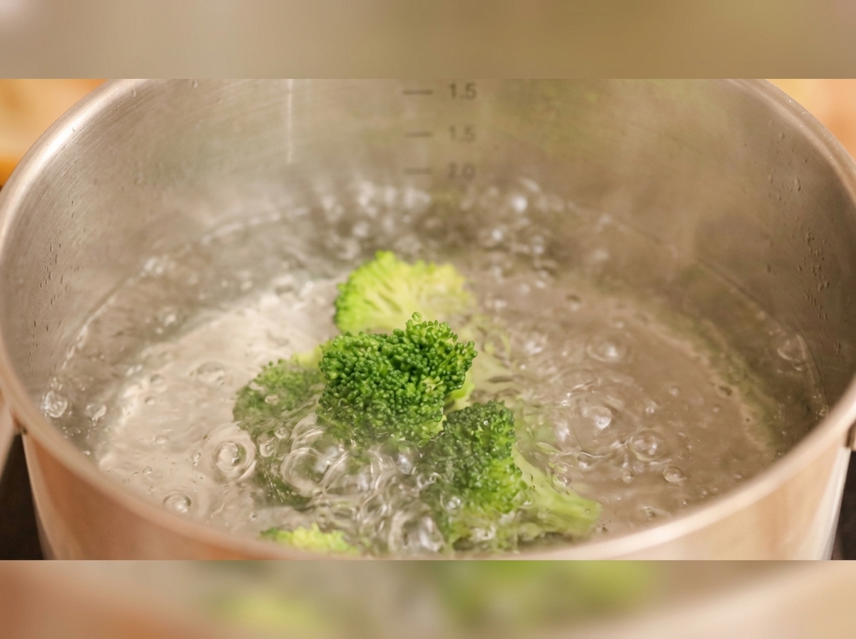 Brócoli y rodajas de zanahoria hirviendo en una olla con agua.