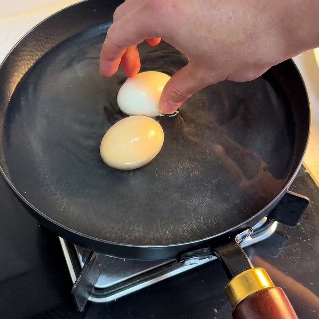 Dos huevos cocidos pasándose a un bol con agua fría.
