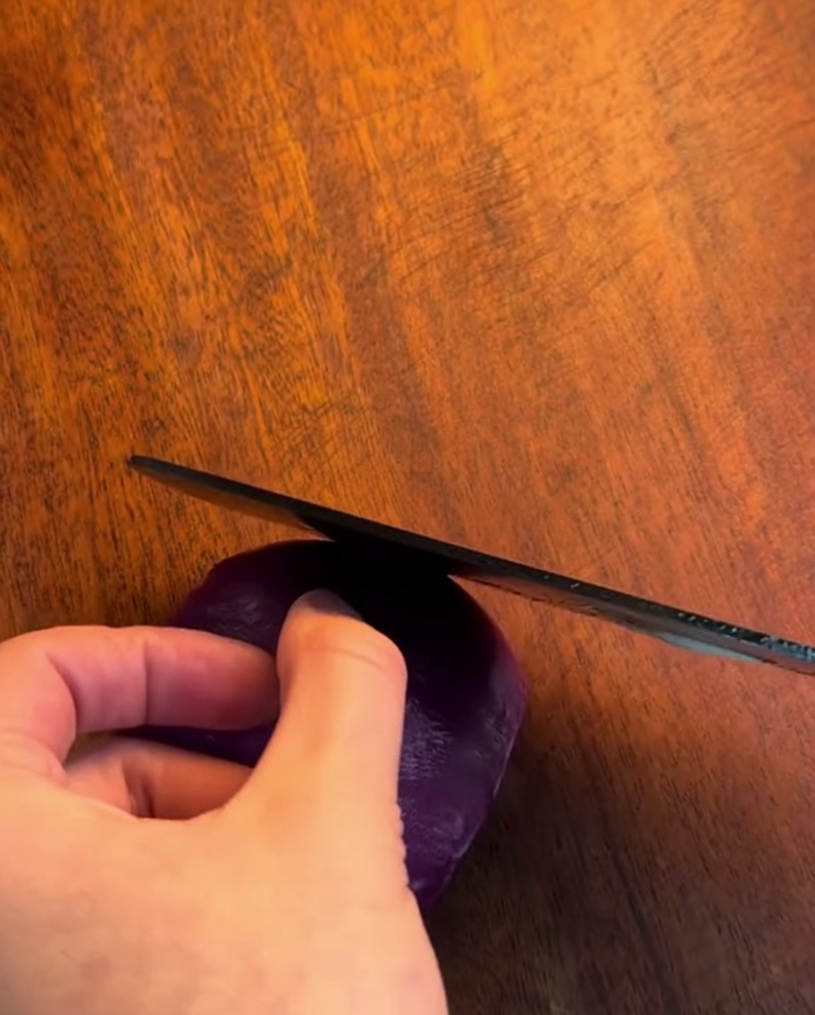 Un cuchillo afilado cortando una cebolla en tiras finas sobre una tabla de madera.