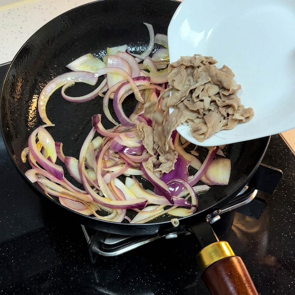Carne blanqueada trasladándose de un plato blanco a la sartén con la cebolla salteada.