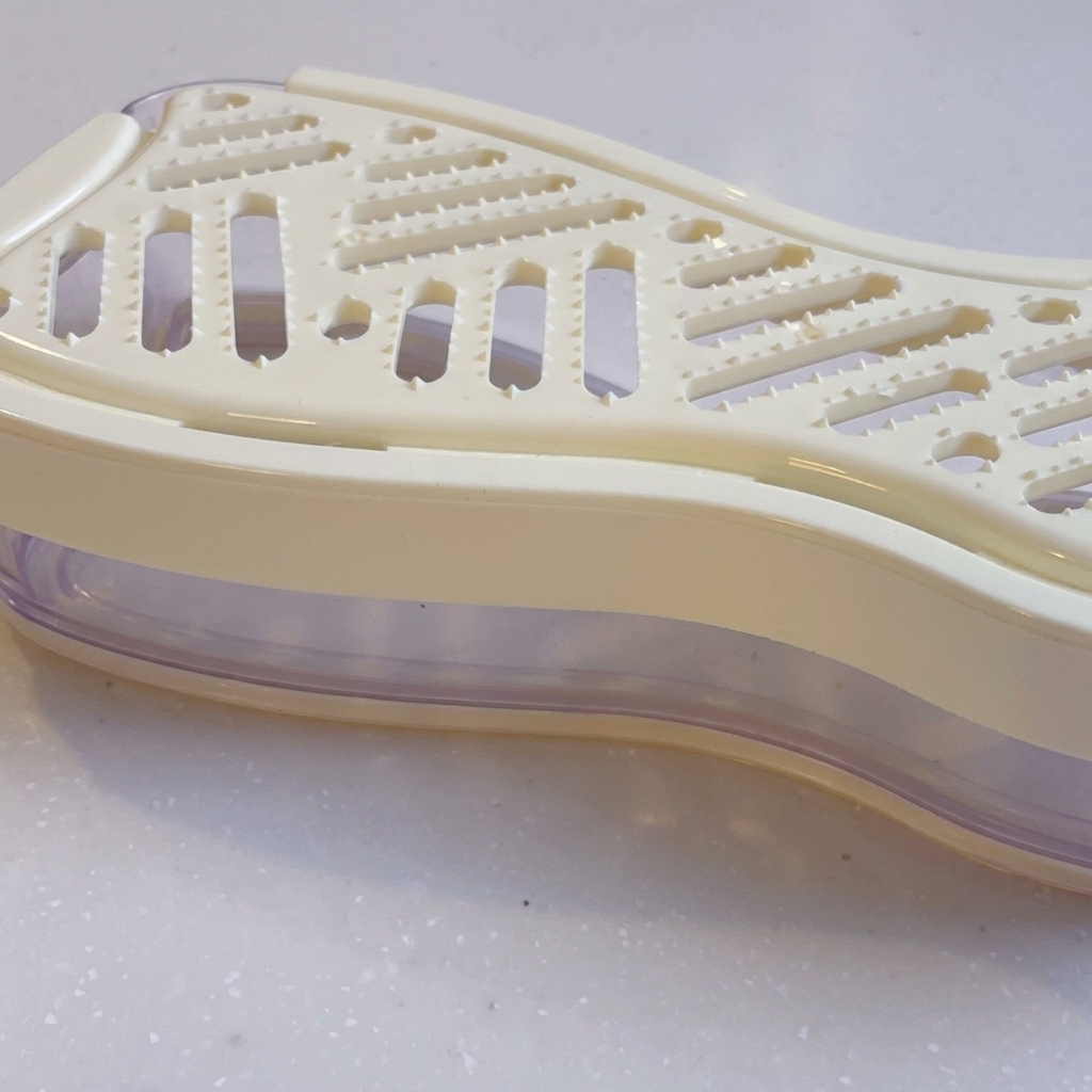 Primer plano de un rallador manual blanco con rábano daikon rallado dentro.