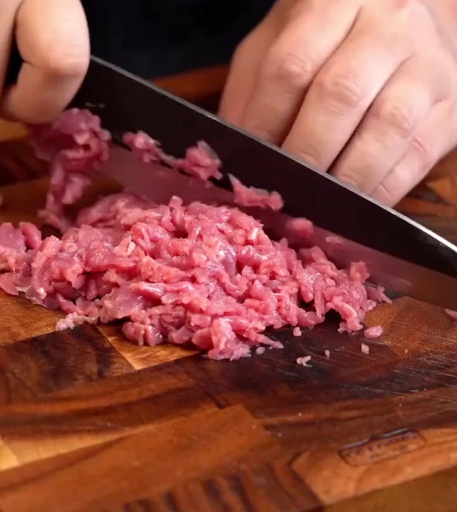 Pasta de carne de res picada fresca sobre una tabla de madera, lista para sazonar.