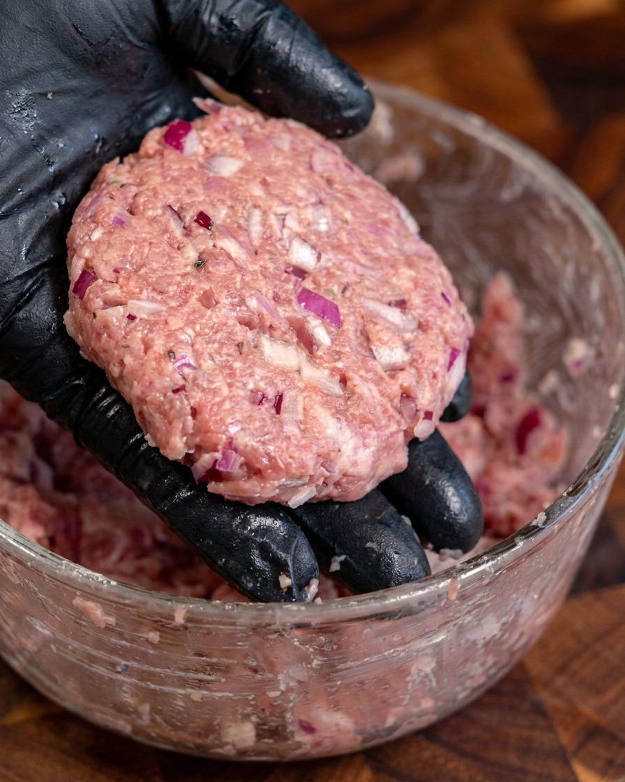 Varias hamburguesas de carne gruesas y redondas moldeadas a mano.