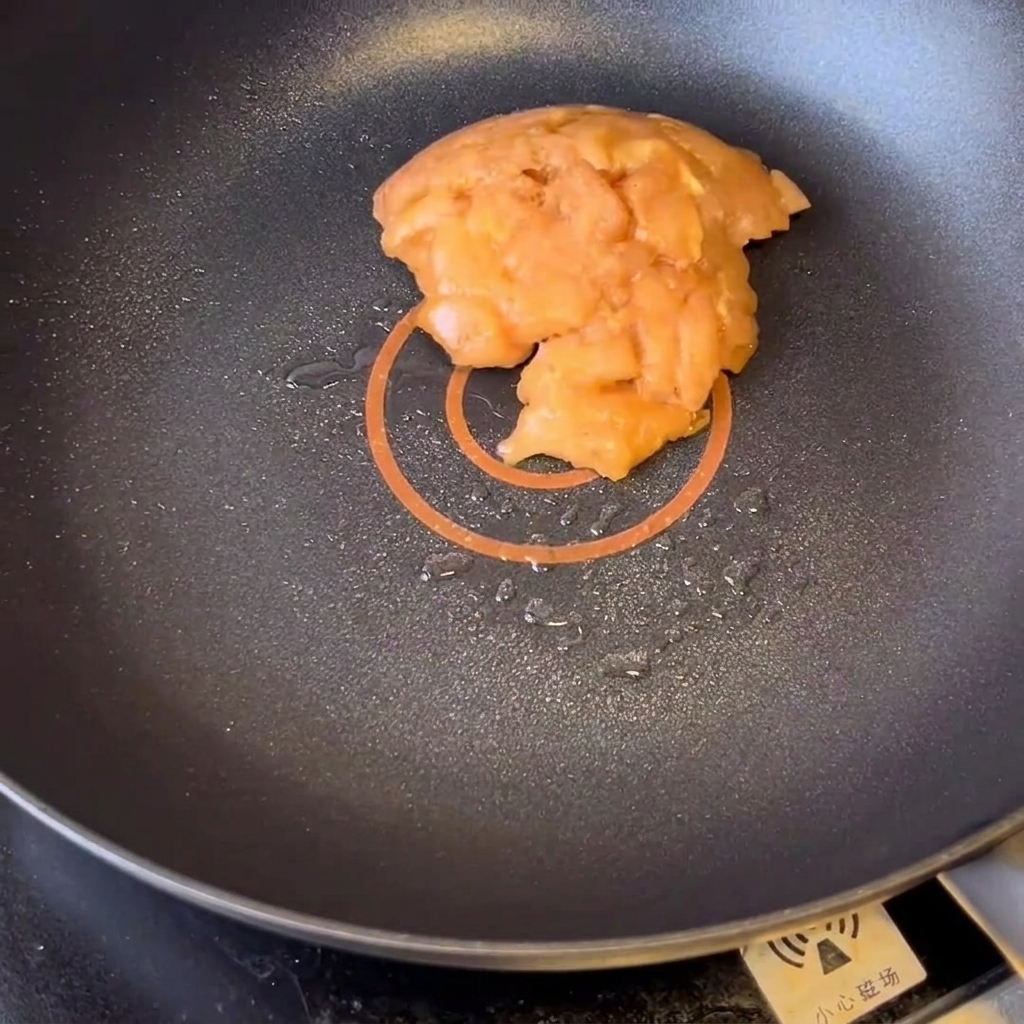 Trozos de pechuga de pollo marinada dorándose en una sartén con aceite caliente.