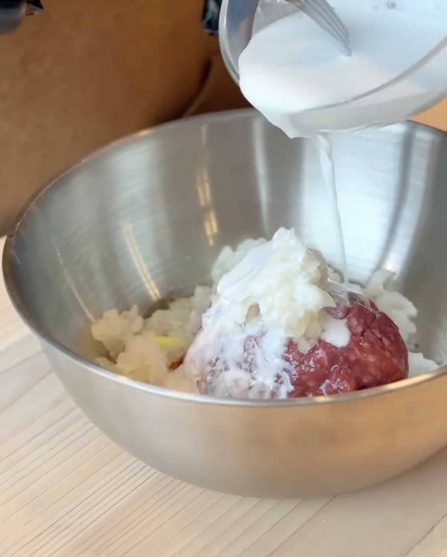 La masa de leche y harina de batata siendo vertida sobre la mezcla de carne picada en un cuenco grande.