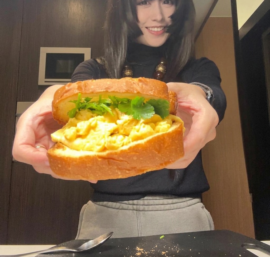 Un sándwich completamente montado sostenido con ambas manos, listo para ser envuelto o cortado.