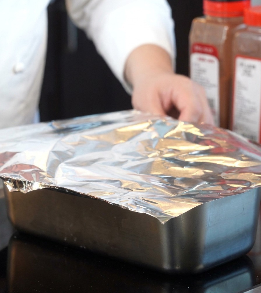 Papel de aluminio siendo utilizado para cubrir herméticamente la bandeja de hornear.