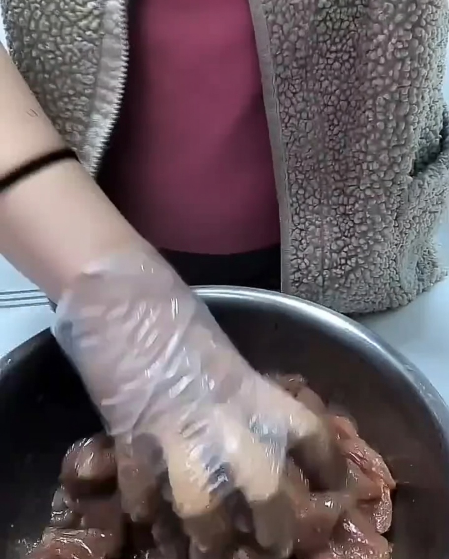 Aceite de cocina siendo vertido sobre los trozos de cerdo sazonados en un bol.