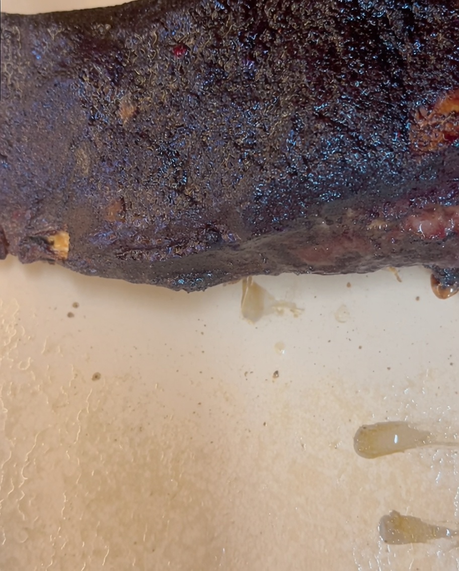 El borde lateral del papel de estraza doblado hacia adentro sobre el extremo de la costilla de res.