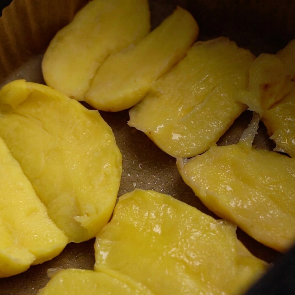 Papas en la canasta de la freidora de aire cubiertas de aceite, siendo sazonadas con sal gruesa y semillas de sésamo.