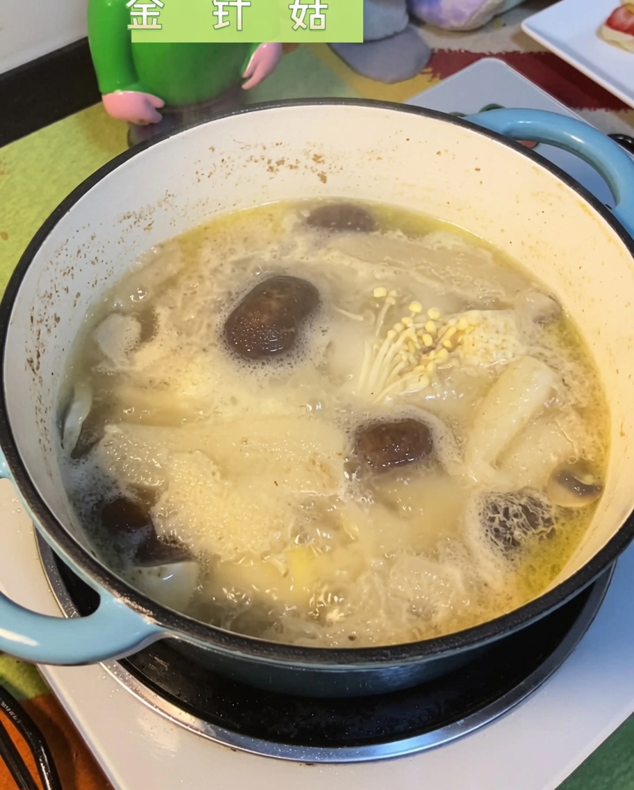 Setas enoki sumergiéndose en el caldo hirviendo de setas y pollo.