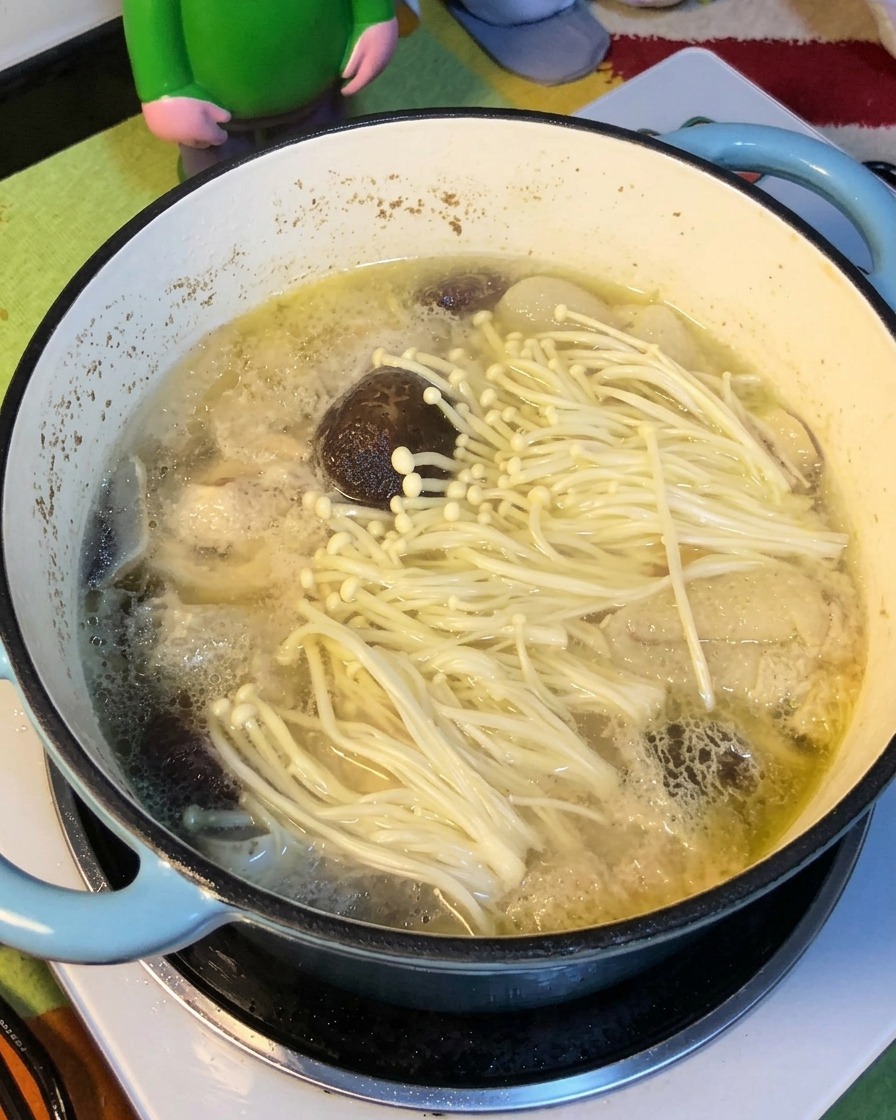 Fideos amarillos ablandándose al ser añadidos a la sopa de pollo y setas.