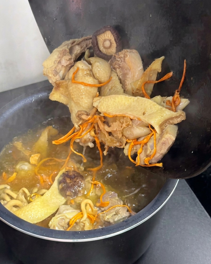 Transfiriendo el caldo de pollo y setas a una olla arrocera eléctrica.