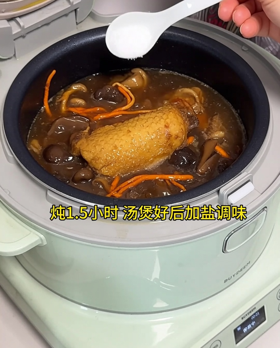Añadiendo sal a la sopa de pollo terminada en una olla arrocera eléctrica.