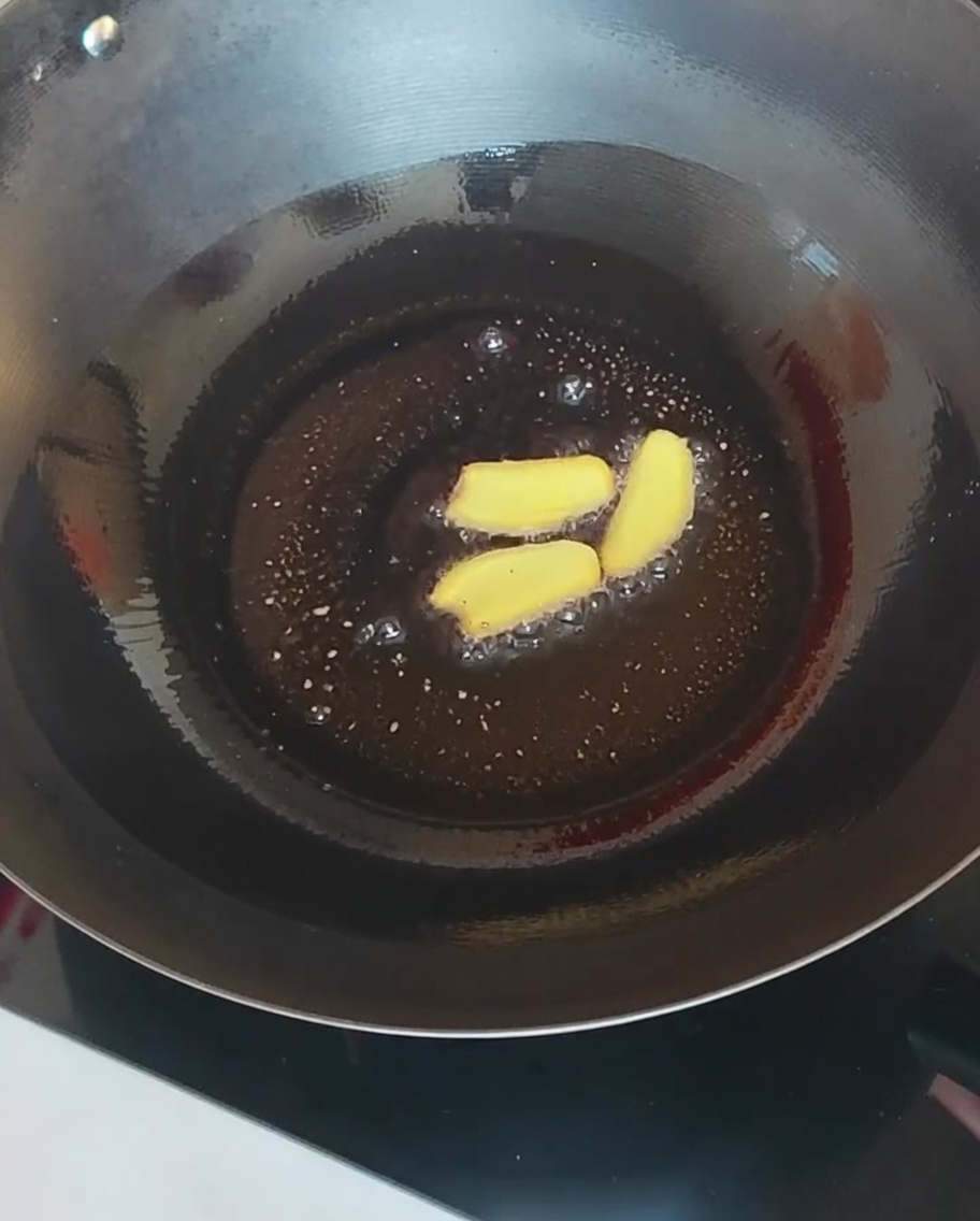 Rodajas de jengibre y varias setas siendo salteadas en un wok caliente.