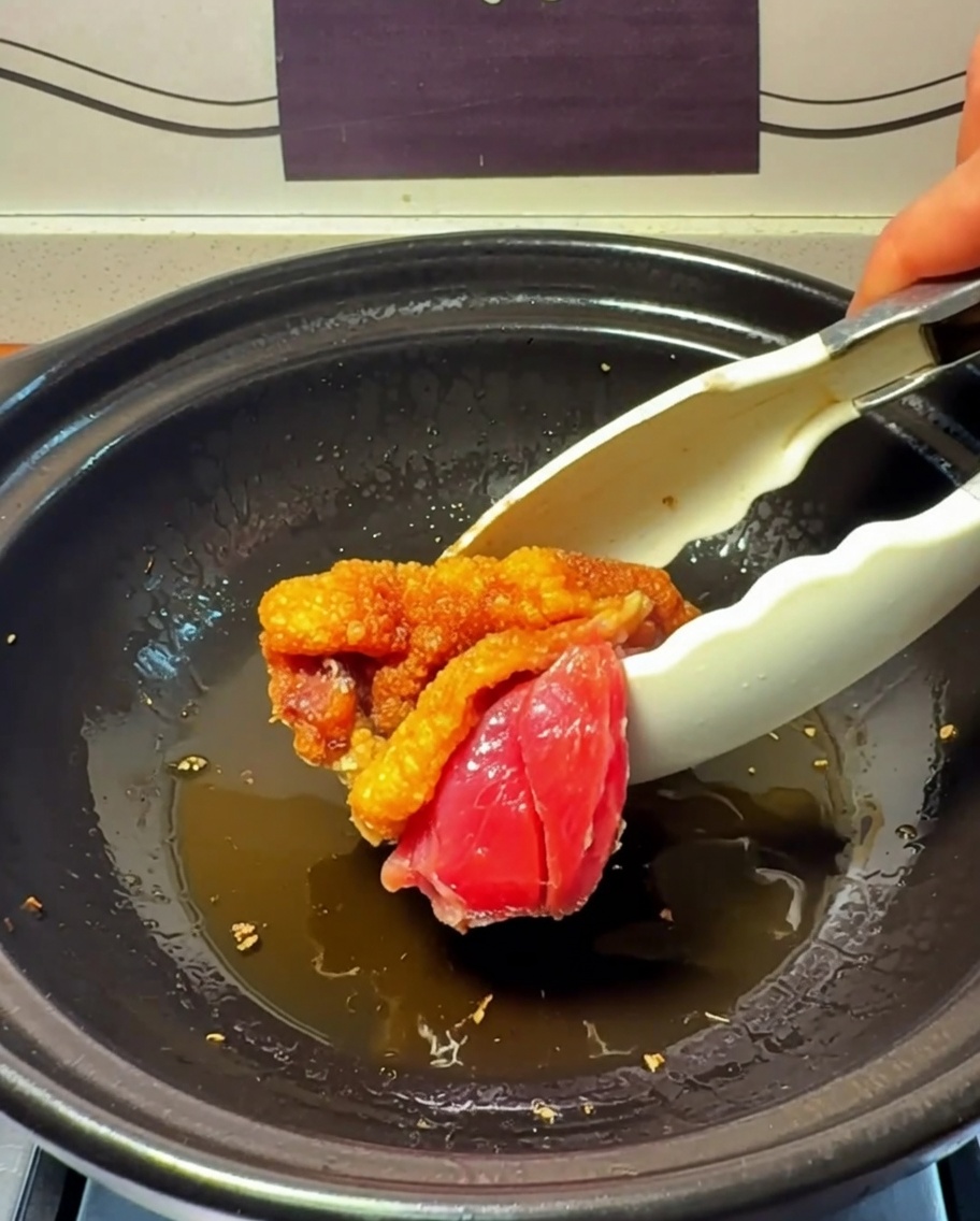 Trozos de pollo sellándose y dorándose en la olla de barro.
