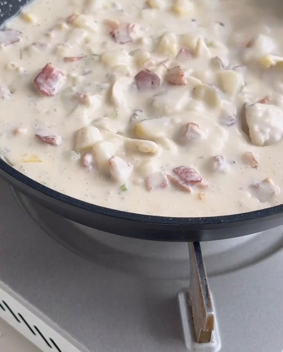 Carne de almeja siendo integrada en la sopa cremosa y burbujeante.