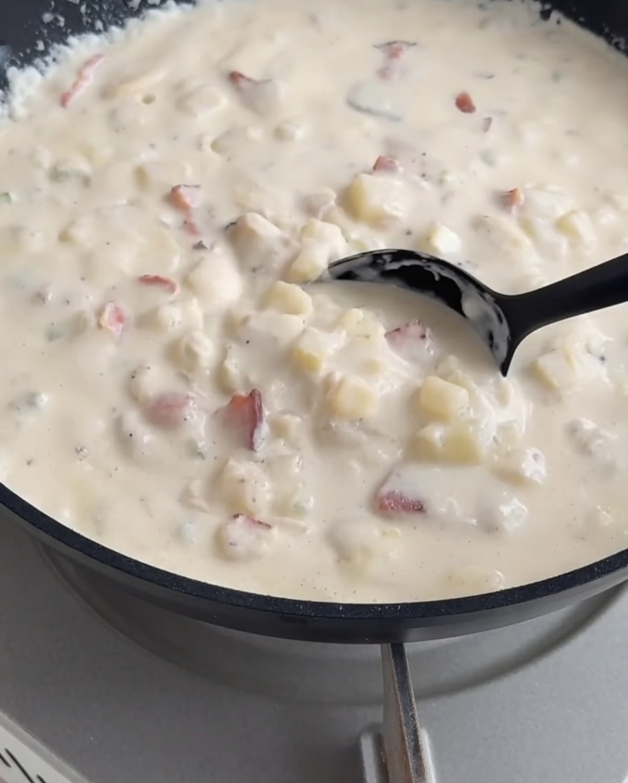 Crema de almejas siendo servida en el cuenco de pan ahuecado.