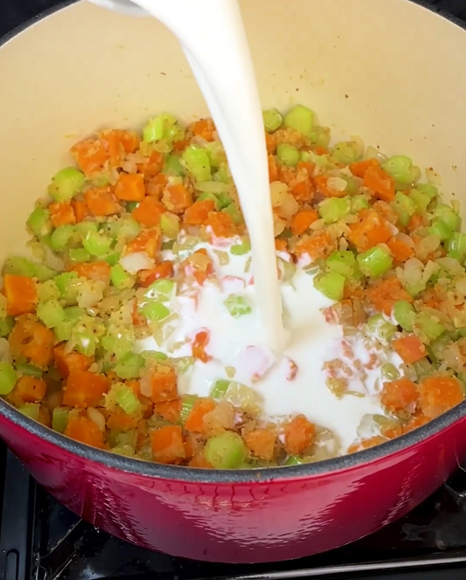 Crema y leche vertiéndose en la olla para crear la base de la sopa.