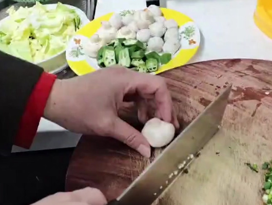 Champiñones siendo troceados en piezas pequeñas sobre una superficie de madera.