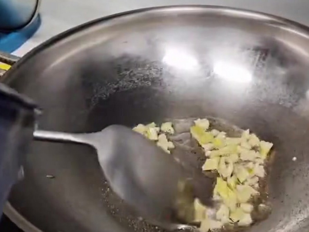Agua vertida en un wok metálico para formar la base de la sopa.