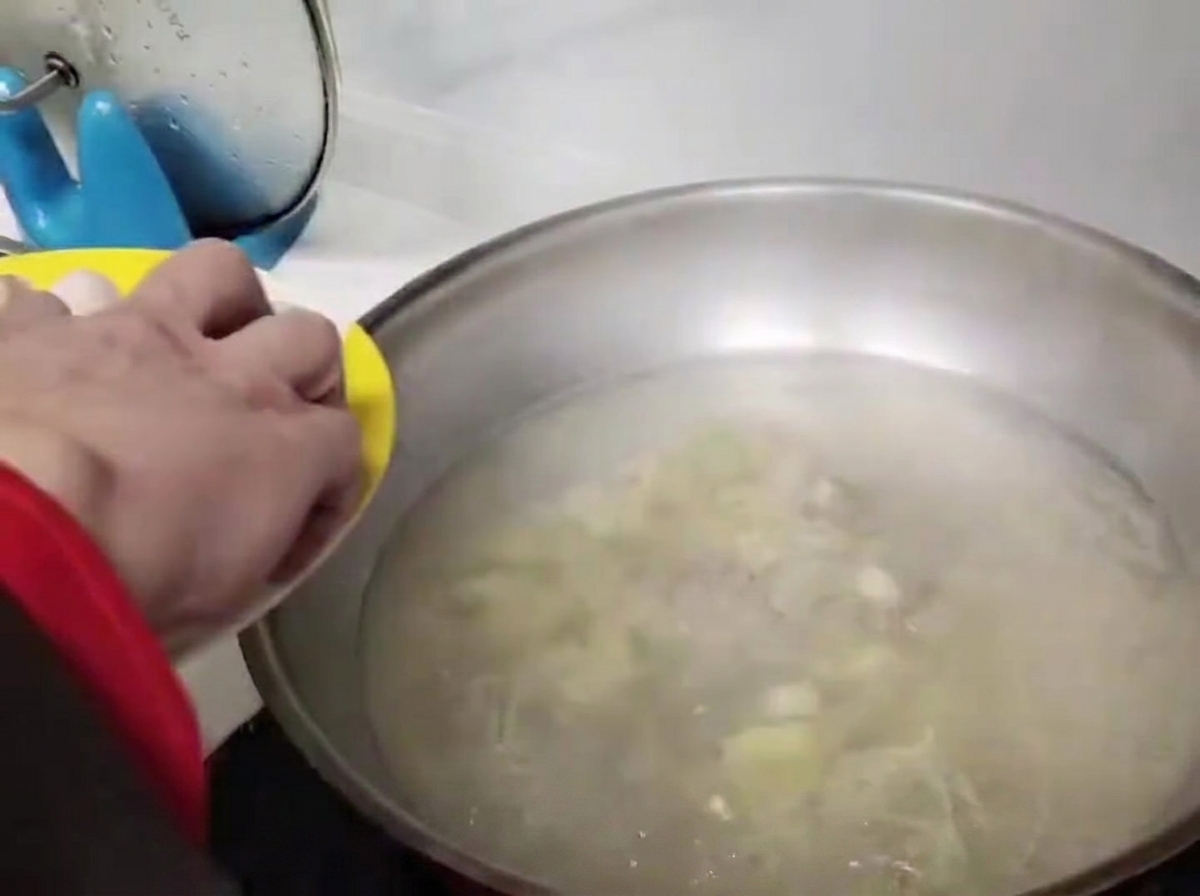Albóndigas redondas siendo colocadas cuidadosamente en el agua hirviendo.