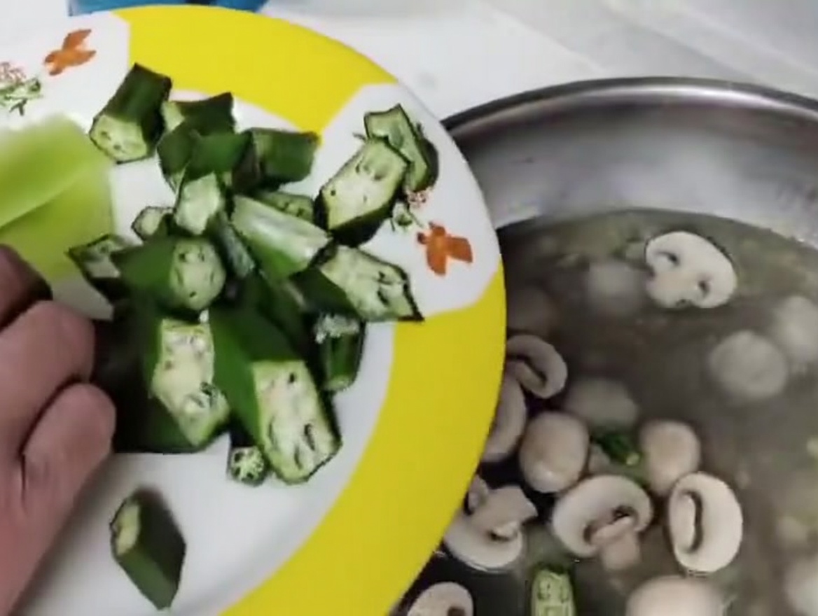 Champiñones troceados y rodajas de okra siendo añadidos a la sopa.