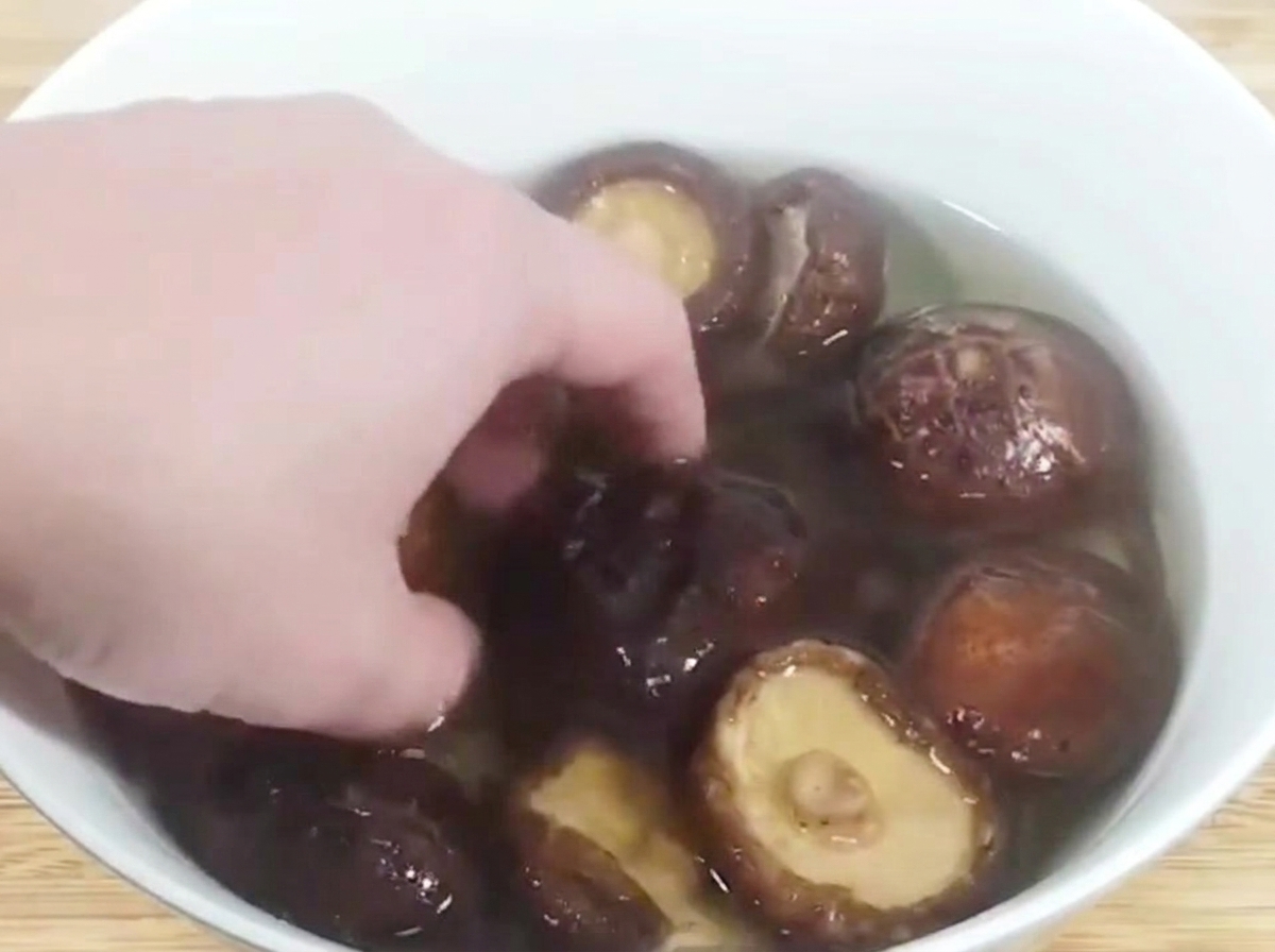 Setas shiitake rehidratadas cortadas en dados apiladas en una tabla de cortar de madera.