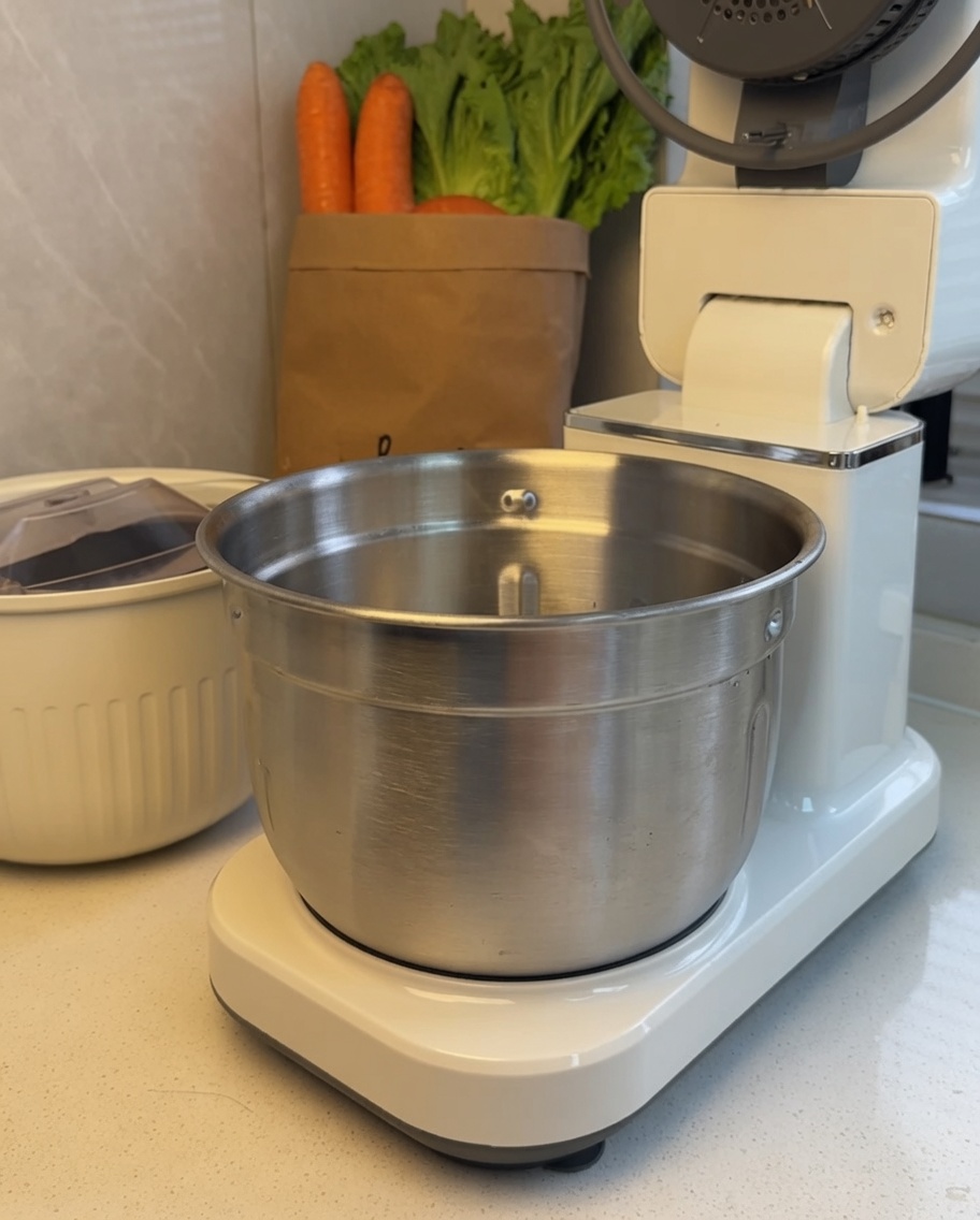 Trozos de carne dentro del tazón de acero inoxidable de una batidora de pie.
